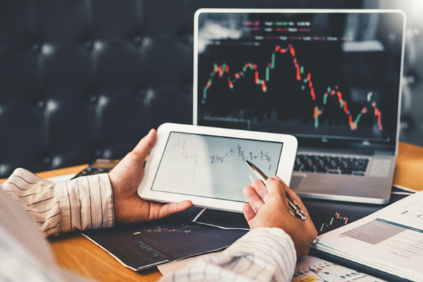 Person studying a financial price chart and trading books as they learn how to trade